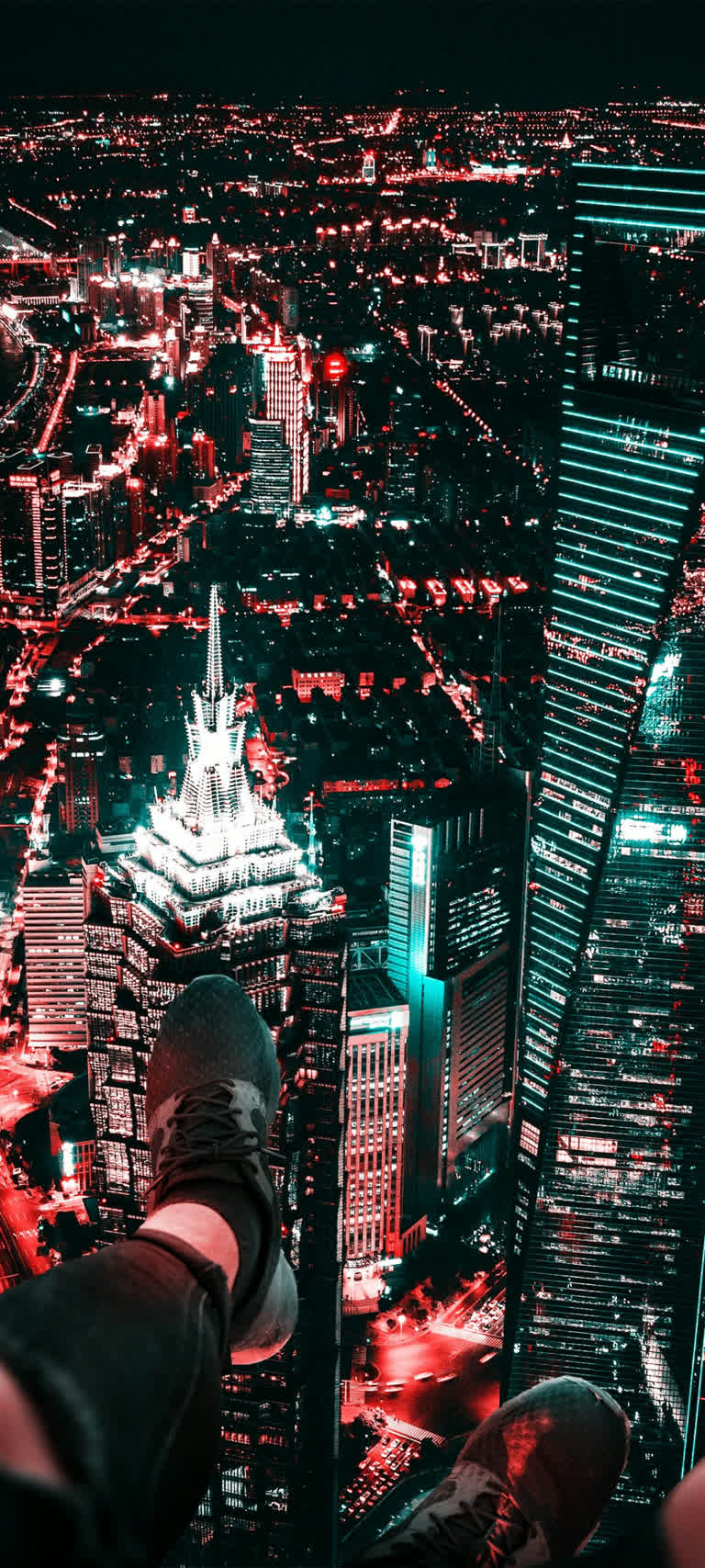 有一个人坐在壁架上,俯瞰着夜晚的城市