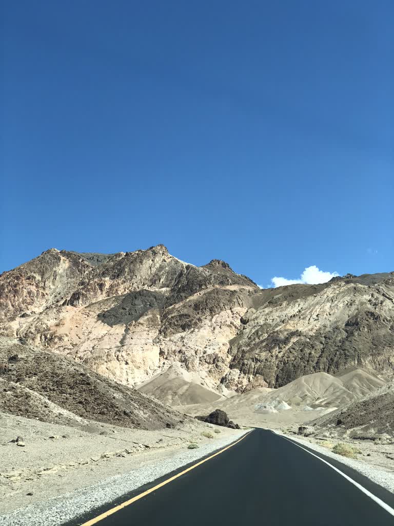 有一条穿过沙漠的路,背景是群山